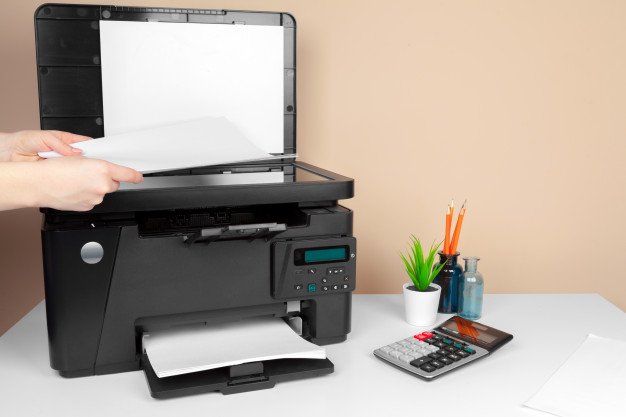 TonerXperts - ¿Porque la impresora no conoce los cartuchos compatibles? - impresora con una calculadora a lado en un fondo simple